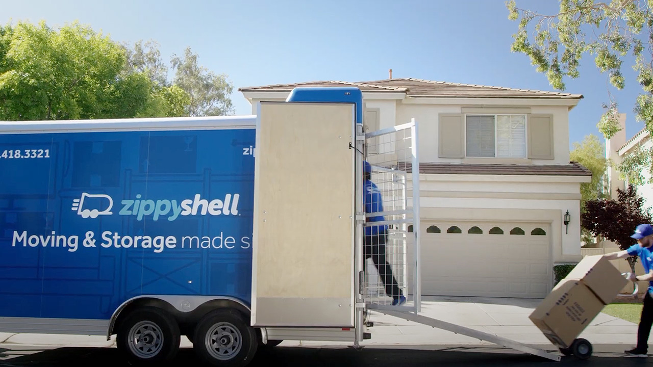 2 men loading a zippyshell trailer in front of a home